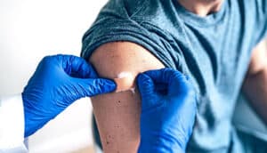 A doctor puts a bandaid over a Covid booster injection site on a man's arm.