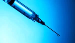 A syringe on a blue background.