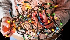 A person holds a string of tangled Christmas lights.