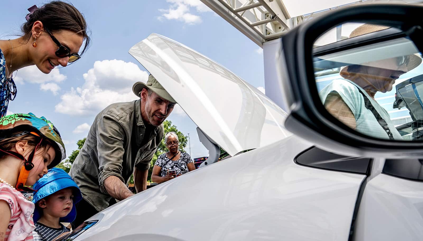 people look under hood of electric car