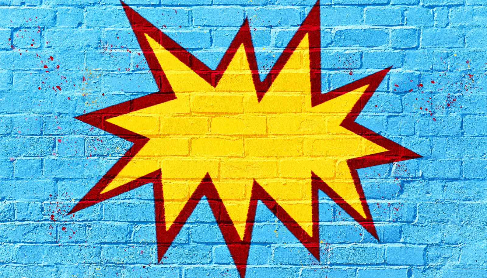 Graffiti of a cartoonish explosion on a blue brick wall.