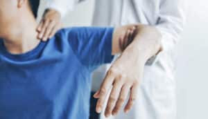 clinician examines patient's shoulder