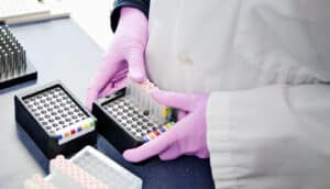 gloved hands hold sample vials in lab