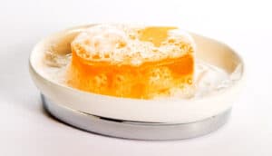 A bar of orange soap in a white dish.