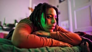 A young woman lays on her bed alone.