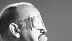 black and white side-view of head with dollar bill taped over eyes