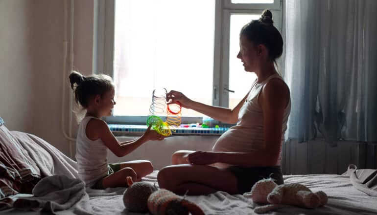 pregnant adult and child play with slinky