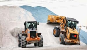 construction vehicles dig from giant piles of rock salt
