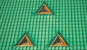 Three small windows in a green tiled roof.