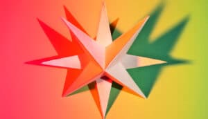 An origami star casts shadows in colorful lighting.