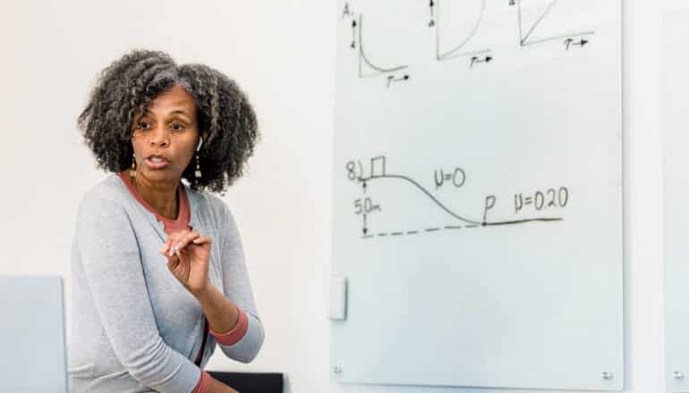 physics professor with formulas on white board