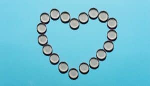 Bottle caps arranged in the shape of a heart on a blue background.