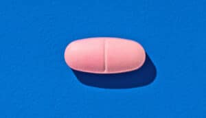 A pink pill on a blue background.