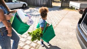 A mother and daughter unload grocery bags from a car.