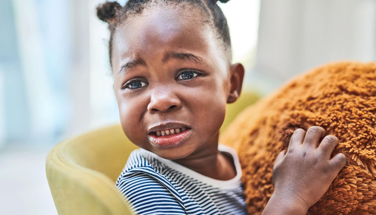 A young girl cries in pain while looking past the camera.