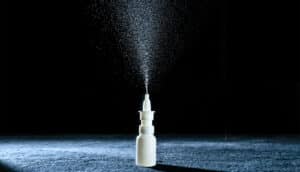 A small white bottle spraying liquid into the air.
