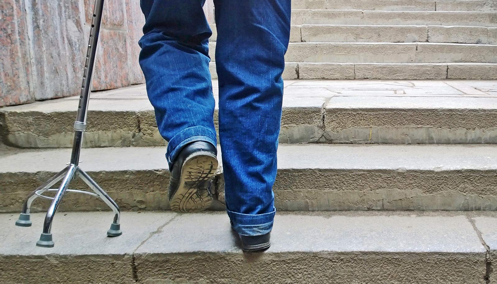 A man walks up stairs with a cane.