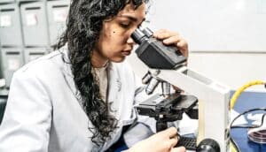 A young woman looks into a microscope.