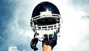 A person holds up his football helmet into the air.