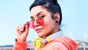 A woman wearing heart shaped glasses looks at the camera.