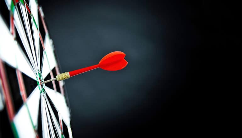 A red dart hits a bullseye on a dart board.