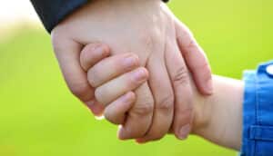 A mother and child hold hands.