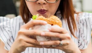 A woman eats a fast food hamburger.