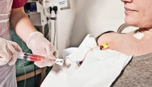 A health worker clears a line going into a patient's body, readying them for chemotherapy.