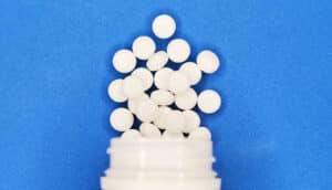 A bottle of aspirin spills onto a blue surface.