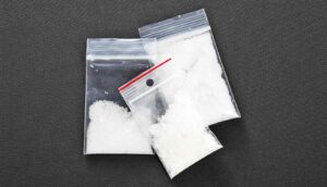 Bags filled with white powders on a black surface.
