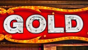 A neon sign covered in small lights that reads, "gold."