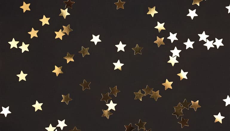 Gold star stickers scattered on black construction paper.