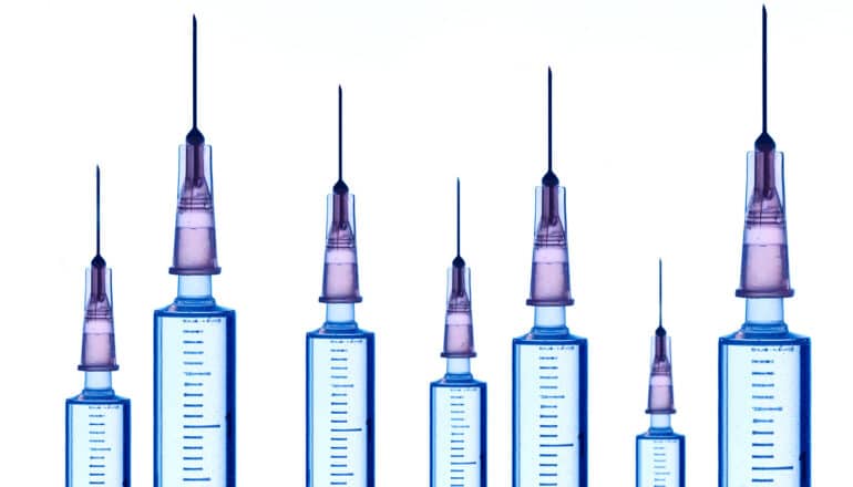 A row of syringes at different heights on a white background.