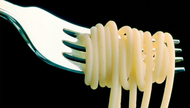 Noodles wrapped around a fork on a black background.