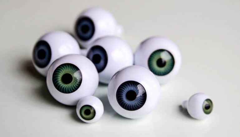 A group of plastic eyeballs sit on a gray surface.