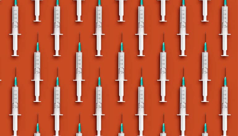 Rows of vaccine syringes on an orange background.