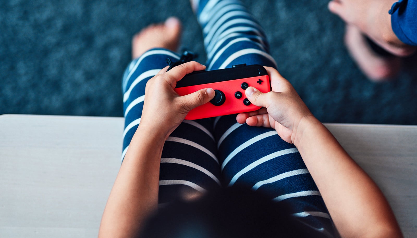 A young child holds a video game controller while sitting on the couch.