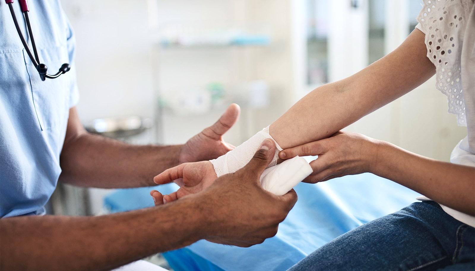 A doctor wraps a bandage around a child's arm.