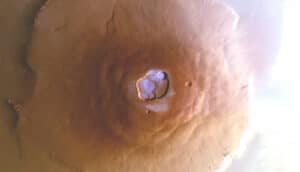 An aerial shot of a the volcano Olympus Mons on Mars with frost on the top shaded in blue.