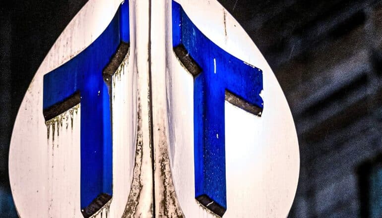 A road sign with two blue letter T's.