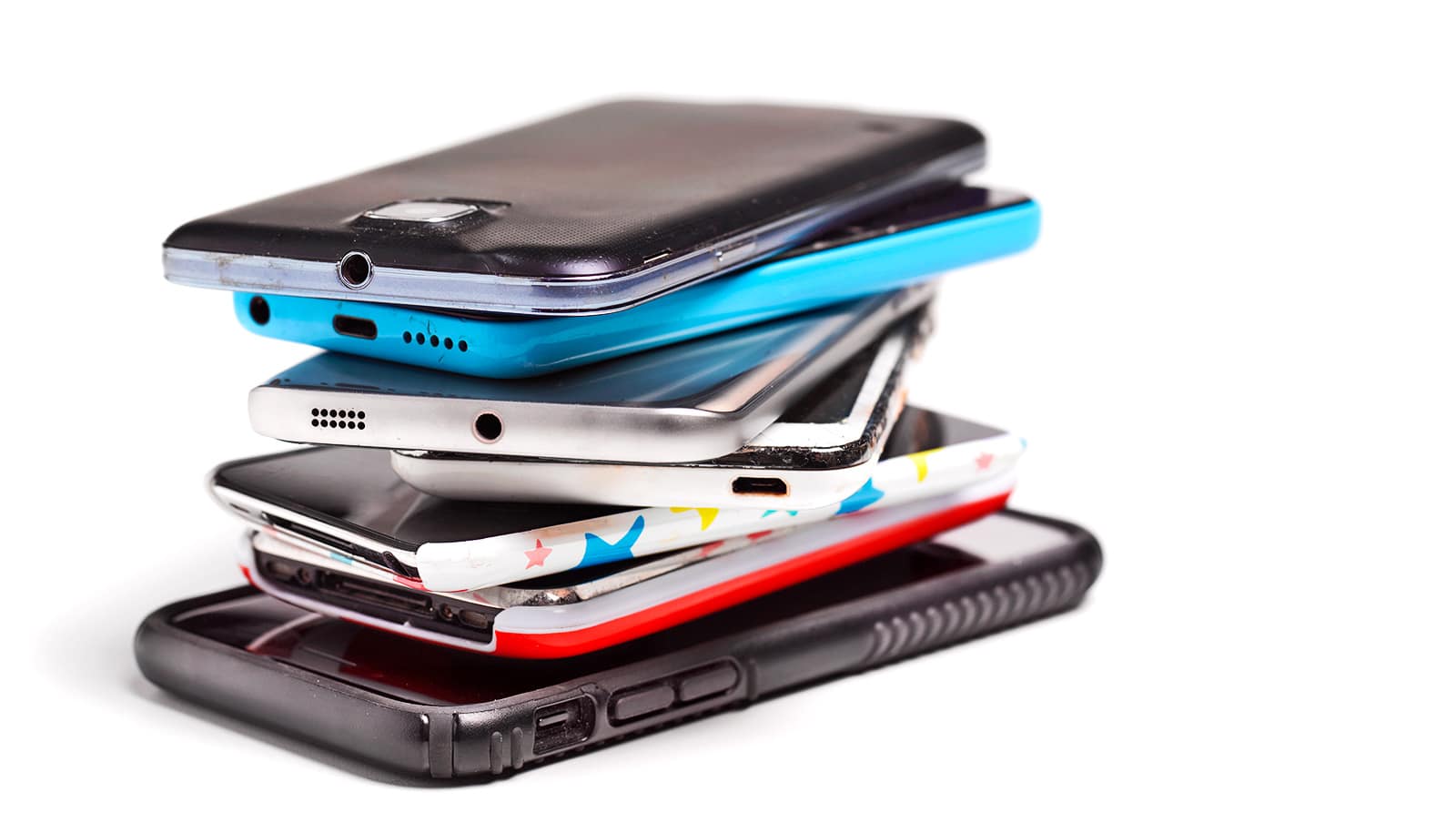 A stack of old phones stands on a white surface.