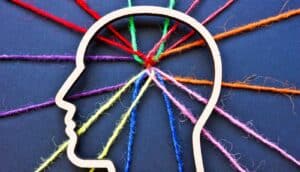 Colorful string leads into the outline of a human head where all the strands are tangled together.