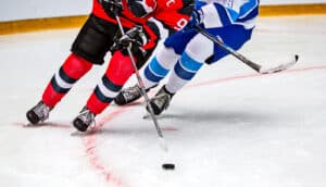 Two hockey players skate after the puck during a game.