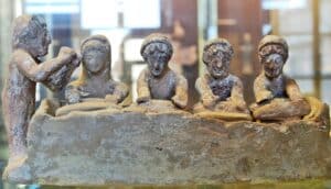 A statue of four people kneading bread while leaning over a table.