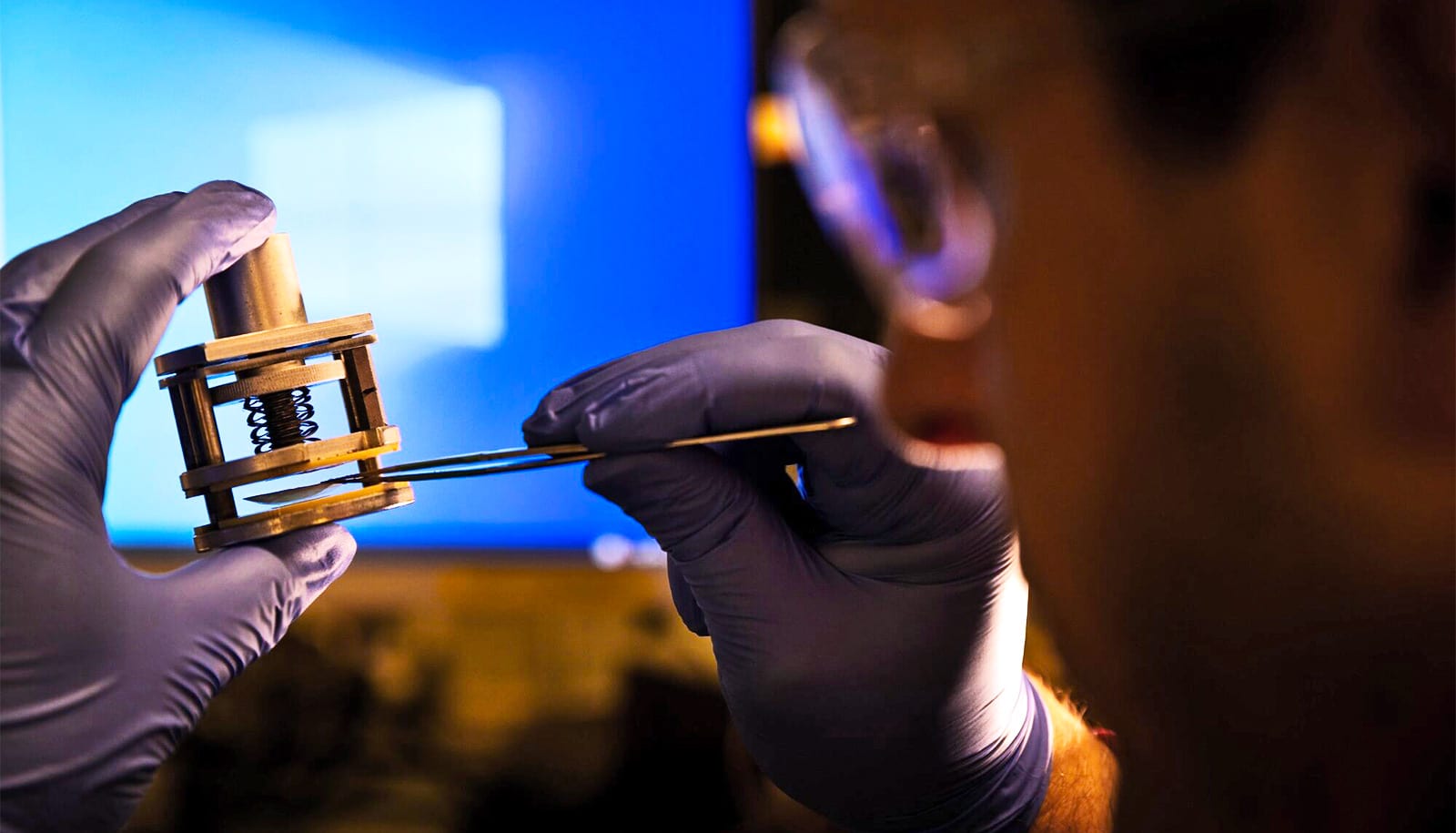 Kamcev holds a filter device in one hand and places the electrodes in it with tweezers in the other.