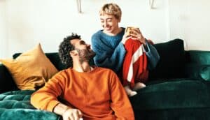 A young couple laugh together while hanging out on their couch.