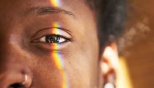 A person's eye has a rainbow-colored refraction of light running across it.