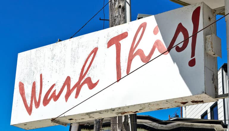 A white sign has the words "wash this" on it in red letters.