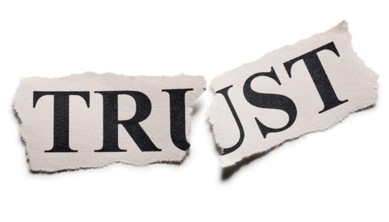 The word "trust" cut out from a newspaper and torn in half.