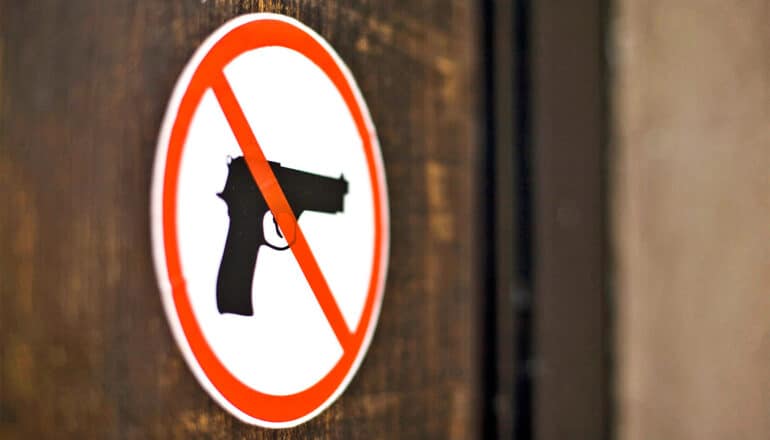 A sign shows a red line through a black handgun.
